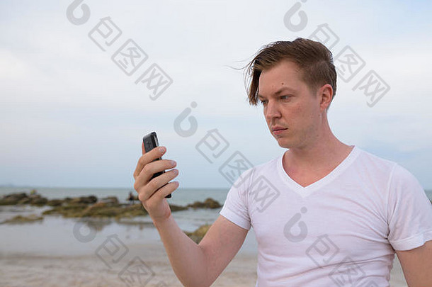 年轻帅哥在花城公共海滩使用手机