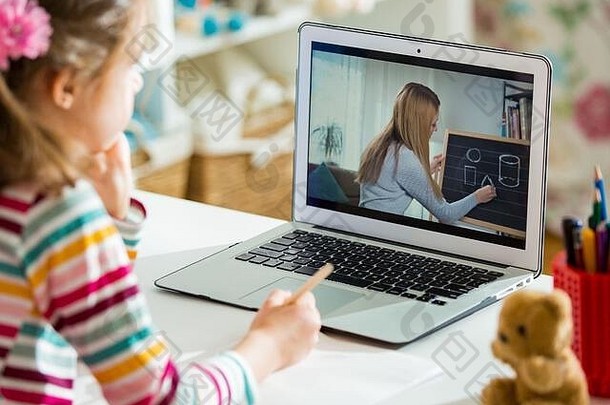 年轻的远程女教师使用网络摄像头与学生进行视频电话会议。在线教育和电子学习概念。家庭隔离距离