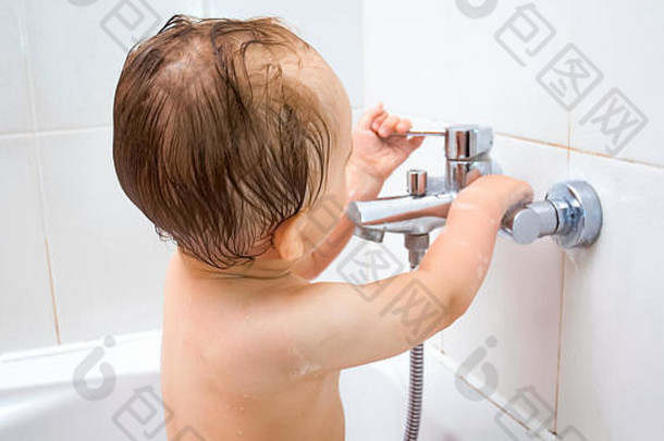 一岁男孩打开浴室水龙头的特写图片