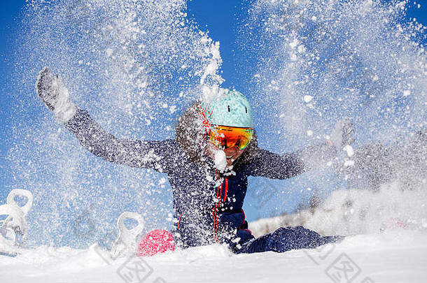 女运动员坐在雪堆里扔雪的照片