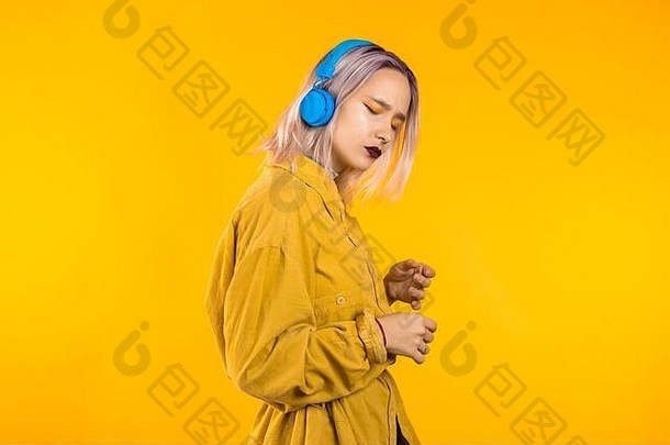 粉红头发的美女戴着耳机在黄色演播室跳舞