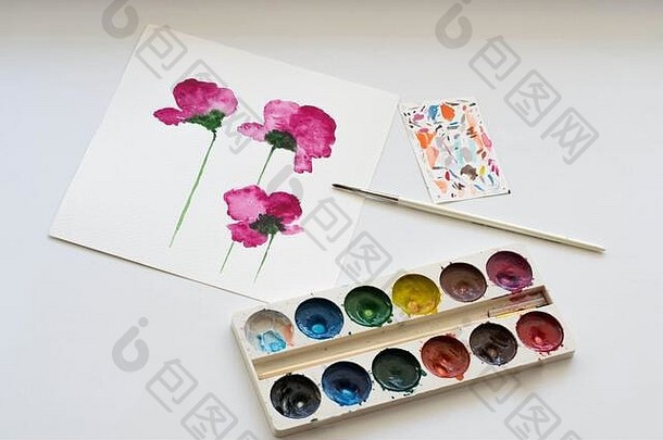 白色桌子上的粉红色木兰花和艺术工具的水彩画。艺术工作场所的静物构成