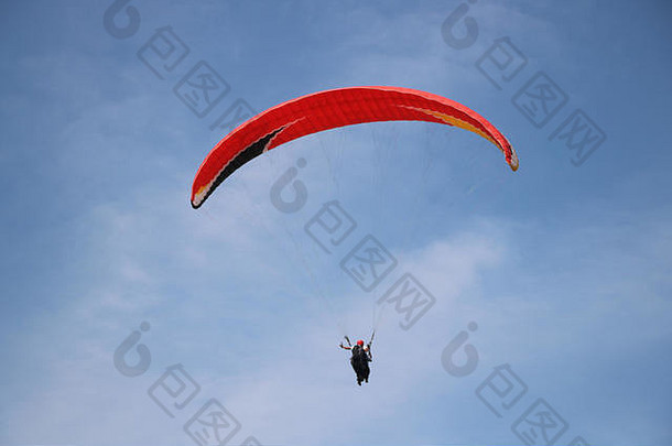 在蓝天白云背景下飞行的滑翔伞。在阳光明媚的日子在天空中滑翔。