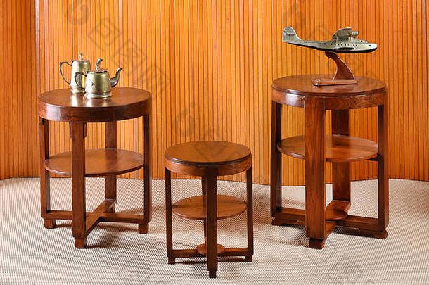 三张木制圆桌上的黄铜茶壶和飞机雕塑