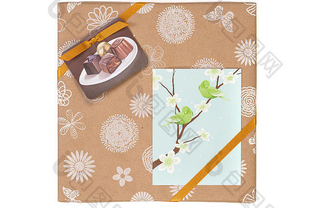 礼品包装盒，白色背景上有巧克力糖果和金色胶带，并附有贺卡。