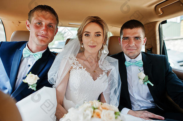 <strong>新娘</strong>坐在豪华婚车的后座上，两名伴郎系着绿松石蝴蝶结。