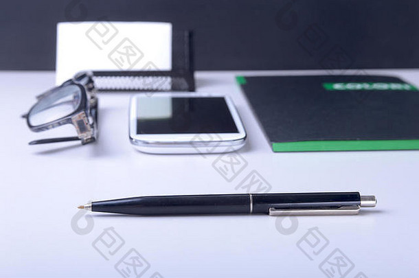 商业概念。卡夫螺旋笔记本、眼镜、智能手机和黑笔的俯视图