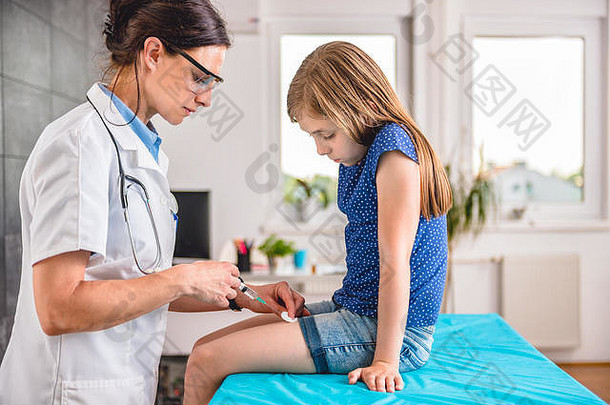 儿科女医生给一个小女孩腿部注射疫苗