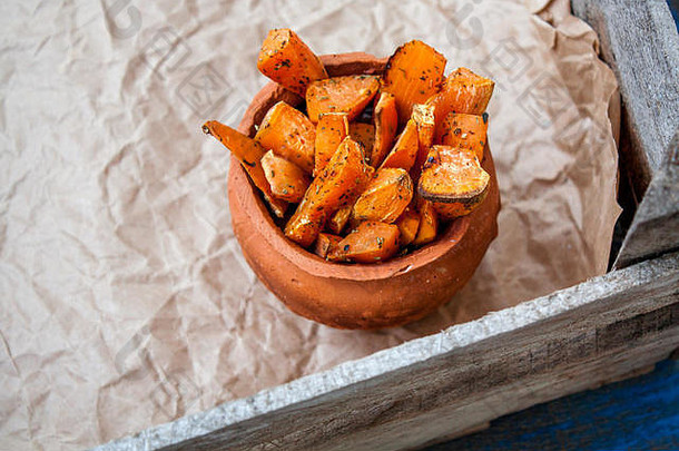 在木制背景上，将烤红薯片和普罗旺斯草药放在锅中。适合排毒饮食或健康膳食。