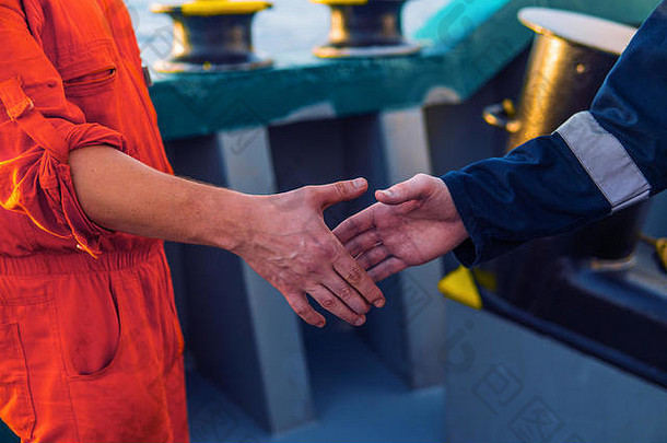 海事承包商商人与船上工人握手。