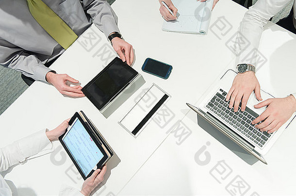 商务人士小组在会议上集思广益的鸟瞰图，以及商人在笔记本电脑和t
