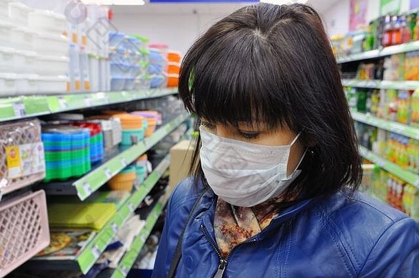 商店里，一位戴着口罩的年轻欧洲妇女在抵抗感染。流行病期间的保护和预防措施。2019冠状病毒疾病