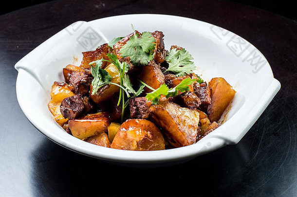 中国人牛肉炖肉年轻的土豆甜蜜的酱汁白色板黑色的背景