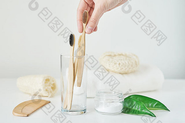女士在浴室内部手持木制竹牙刷。无塑料零废物概念。环保玻璃牙刷、毛巾、牙粉