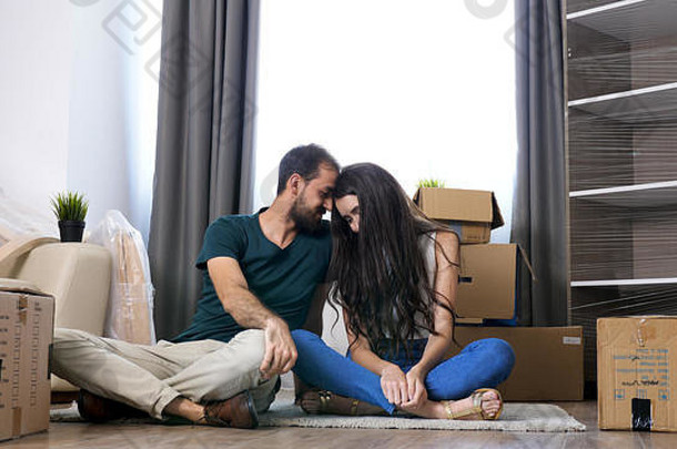 一对年轻夫妇搬进了新家。打开行李后坐在地板上放松