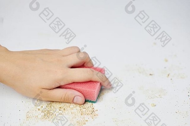 女人手上的海绵可以去除污垢、面包屑和剩菜。清洁厨房的桌子。家务