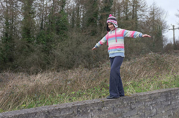 一个9岁的女孩在<strong>墙</strong>上行走时保持平衡