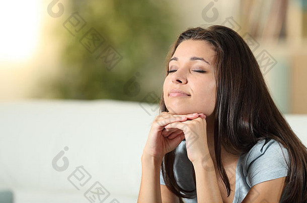 放松的女人坐在家里的沙发上沉思着闭上眼睛