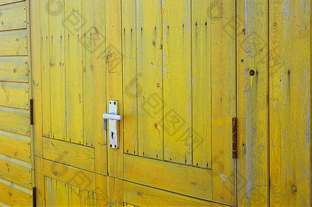 小屋、棚屋、小亭或隔间上亮黄色木门的特写细节，带铝制门把手