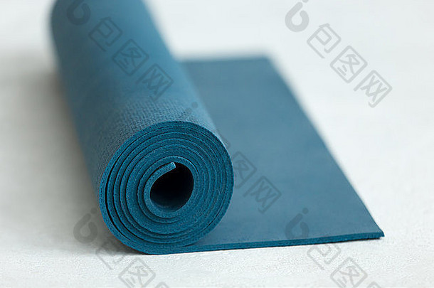 在地板上卷起蓝色瑜伽、普拉提或运动垫，特写