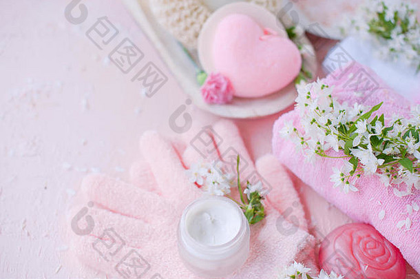 spa手部护理、海盐、奶油和手套。这些花是白色的。粉红色背景。放置文本