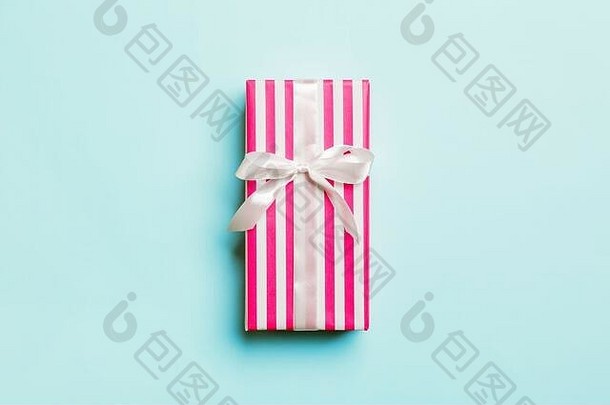 用蓝色背景上的白色丝带用纸包装的圣诞节或其他节日手工礼品。礼品盒，彩台礼品装饰，t