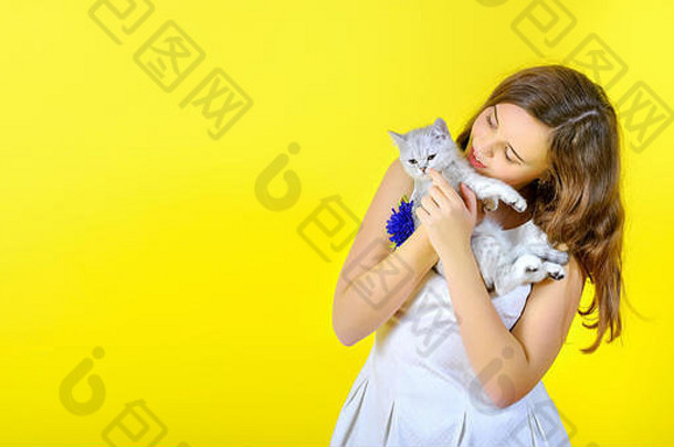 黄色背景的美丽<strong>女孩</strong>抱着一只可爱的小<strong>猫</strong>。放置文本