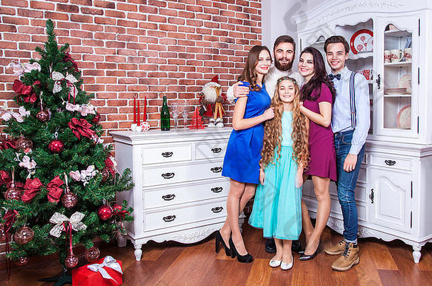 美丽的年轻家庭享受圣诞节时光，用爱拥抱，享受快乐，看着相机。室内，摄影棚拍摄