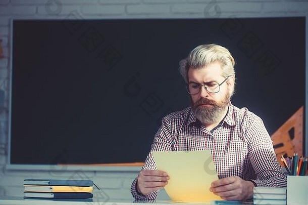 英俊的男老师在教室里检查作业。