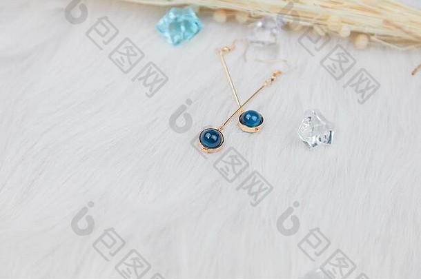 蓝色金属耳环的特写镜头。由蓝色圆形珠子和金黄色金属制成。羽绒被和美丽的干花被用作装饰品。