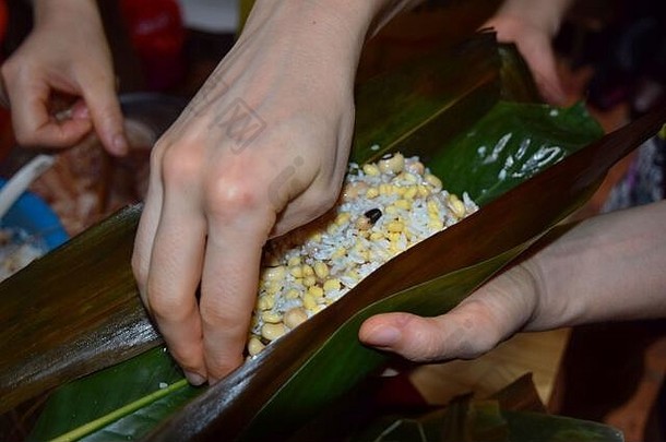制作粽子，这是一道传统的中国米饭，由糯米填充不同的馅料，用竹叶包裹而成。