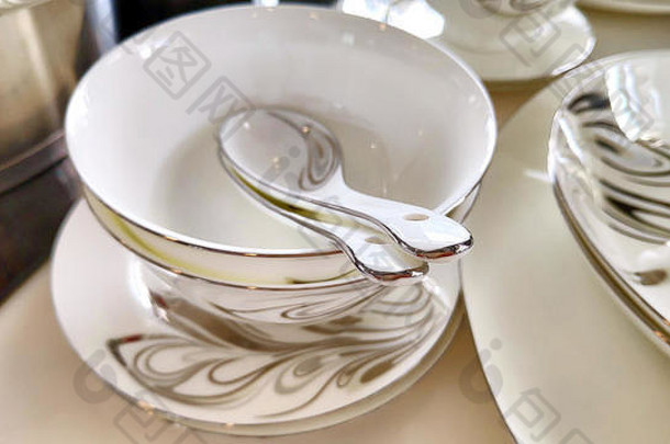 一堆陶瓷盘子碗勺子瓷器优雅的白灰色装饰花卉图案白色桌子上的古董餐具