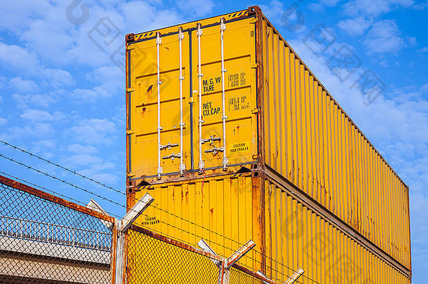 黄色的金属工业货物容器堆放蓝色的多云的天空