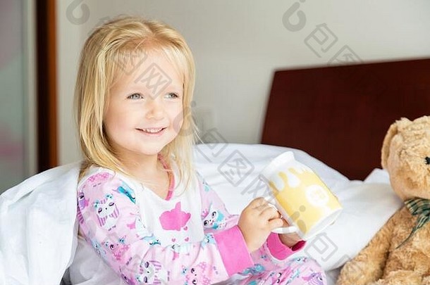 可爱的金发小女孩和玩具熊坐在床上。快乐的童年。COVID-2019冠状病毒疾病的家中滞留