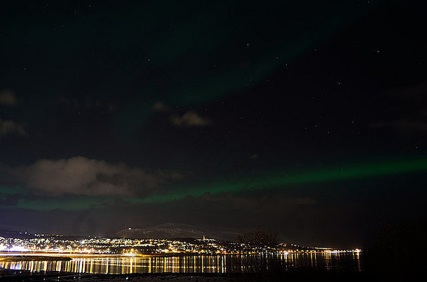 壮丽的北极光覆盖着北极的城市灯光、峡湾和山地景观