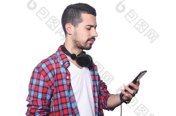 一位年轻的拉丁男子用智能手机打字，戴着黑色耳机的肖像。孤立的白色背景。
