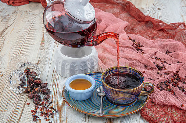 玫瑰果茶：在木制背景上冲泡茶、茶道、一杯新鲜酿造的玫瑰果茶。