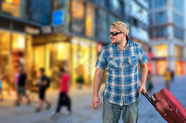 戴太阳镜的游客提着手提箱站在街上