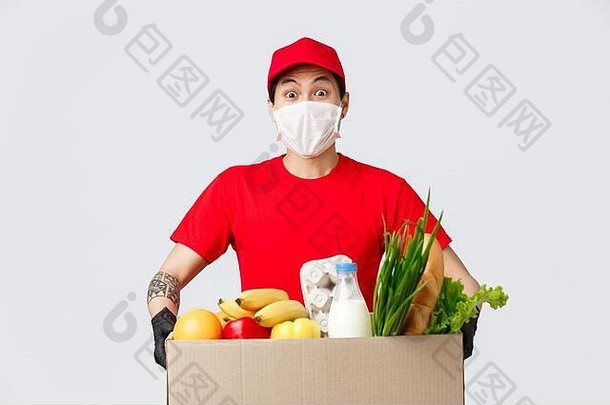 网上购物、食品配送和冠状病毒大流行概念。友好的亚洲送货员，戴着医用口罩和手套，拿着新鲜的包装