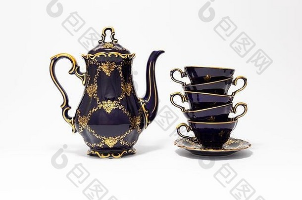 一套美丽的钴蓝色复古瓷<strong>茶具</strong>的特写镜头，白色背景上有金色<strong>花</strong>朵图案。这套设备包括一个茶壶和一个茶壶