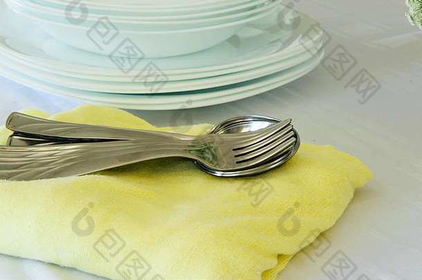 新鲜的白色和黄色餐具套装：餐巾、盘子和银餐具