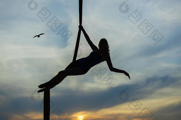 女空中杂技演员在夕阳的背景下<strong>表演</strong>特技。