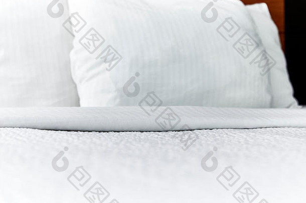 在浅景深的人造床上折叠白色床罩和枕头