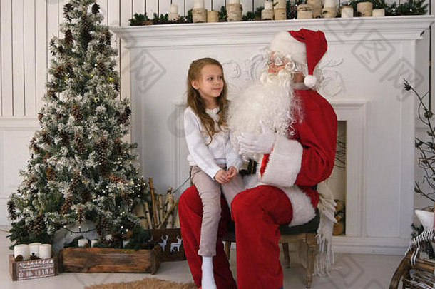 坐在圣诞老人膝上唱圣诞歌的可爱小女孩