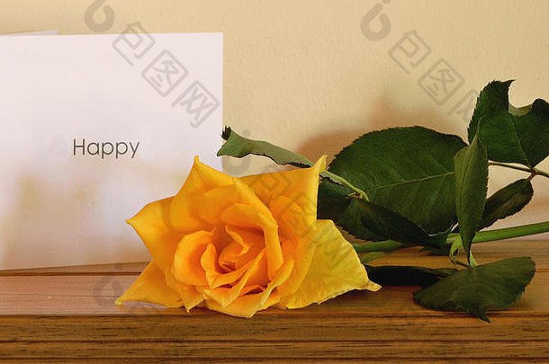 黄玫瑰和一张快乐的白卡（木质表面）