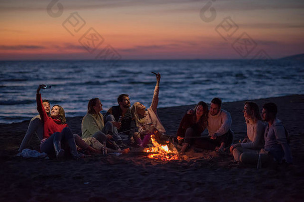集团朋友细胞手机篝火秋天海滩聚会，派对喝啤酒有趣的