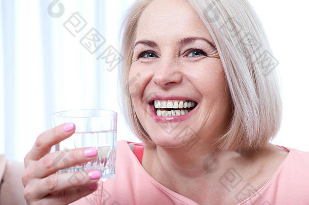 肖像美丽的中间岁的女人喝水早....