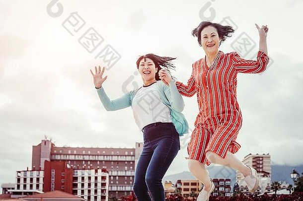 亚洲妈妈和女儿在户外跳跃-快乐的家庭在户外跳舞和庆祝-老年人和年轻人的概念