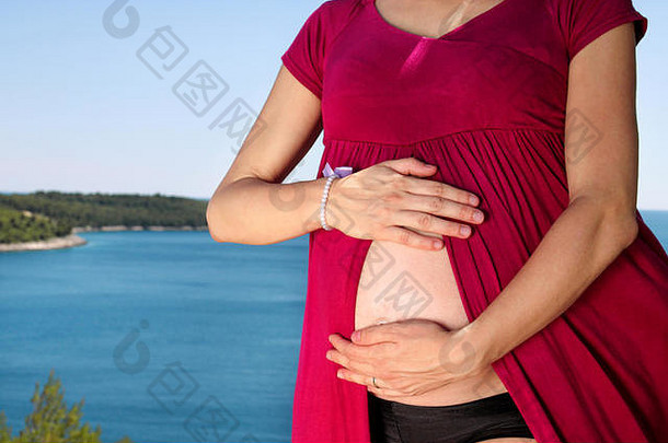 美丽<strong>的</strong>孕妇和女士站在自然环境中，抱着她怀孕<strong>的</strong>肚子。等待婴儿。<strong>妈妈牵</strong>着贝尔<strong>的手</strong>