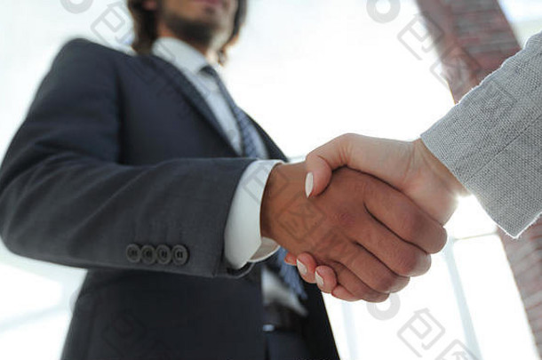 在会议上，兴奋微笑的商人与合作伙伴握手，